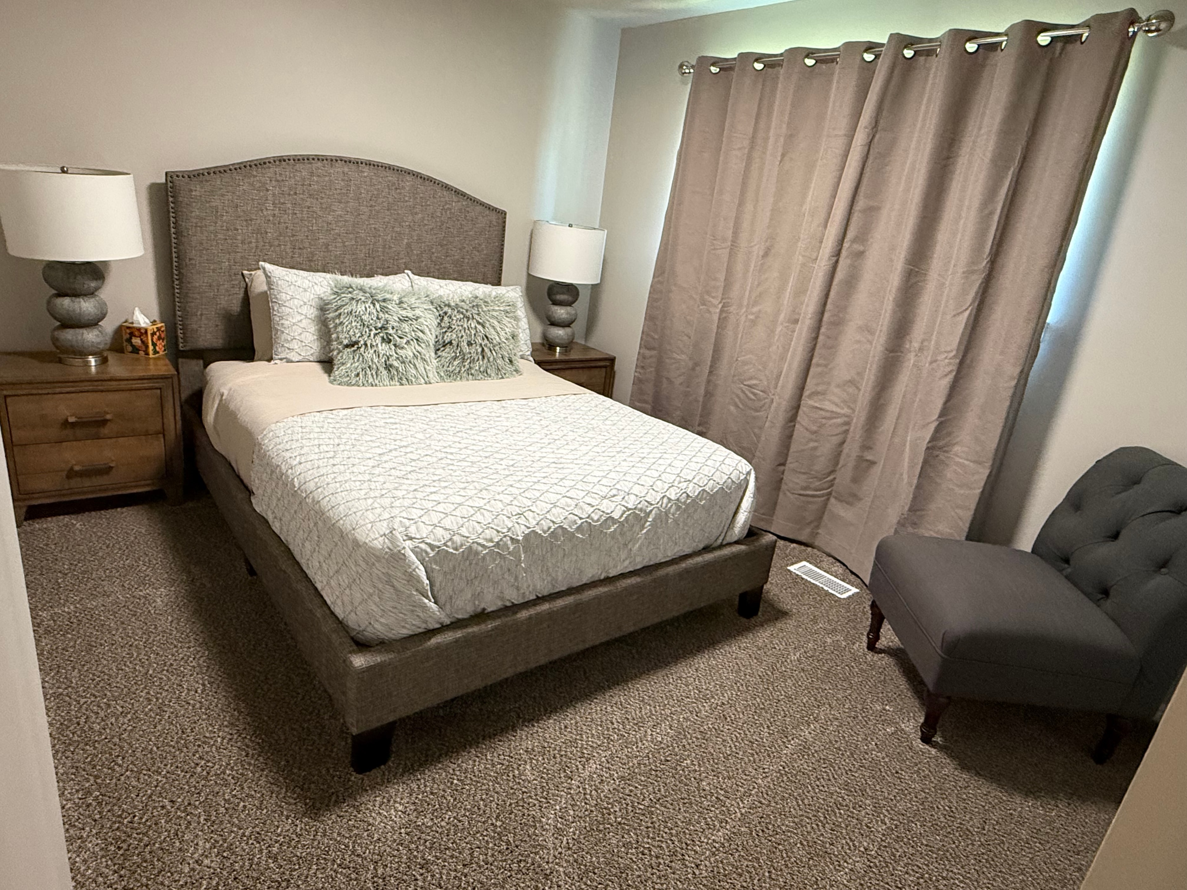 Bedroom with upholstered headboard and tufted accent chair