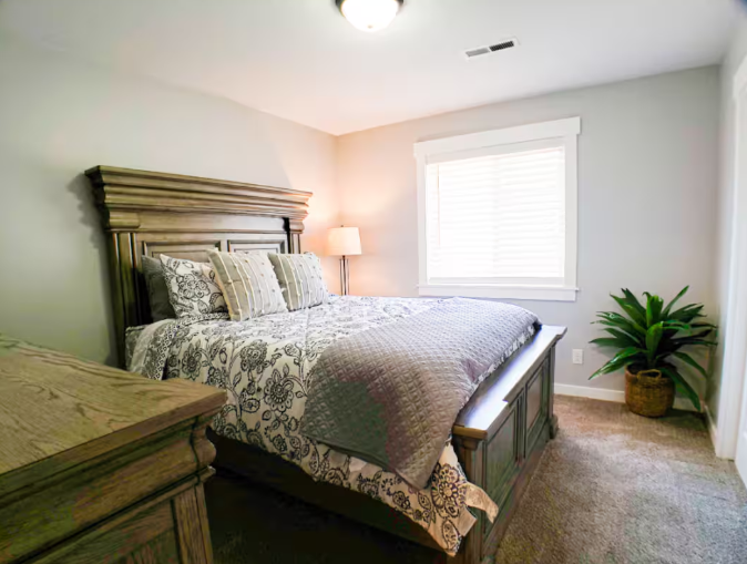 King bedroom with rustic wood headboard, natural light and potted plant
