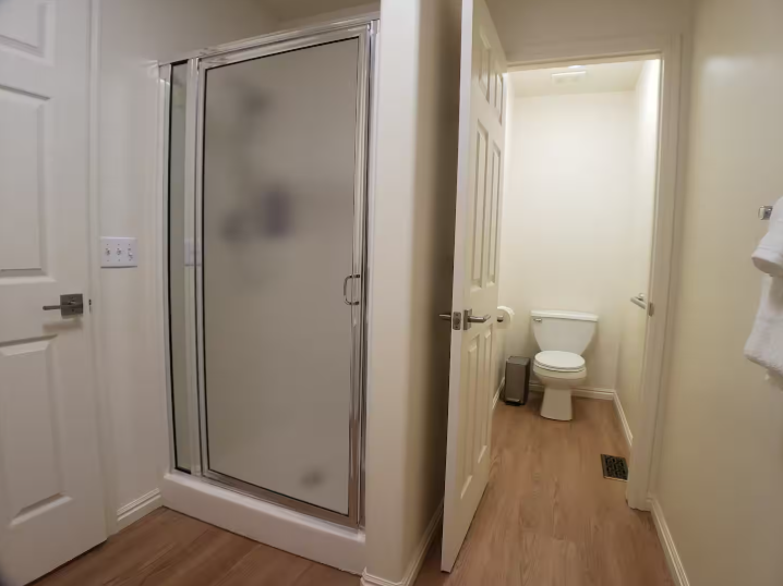 Bathroom with frosted glass shower enclosure and separate water closet with toilet