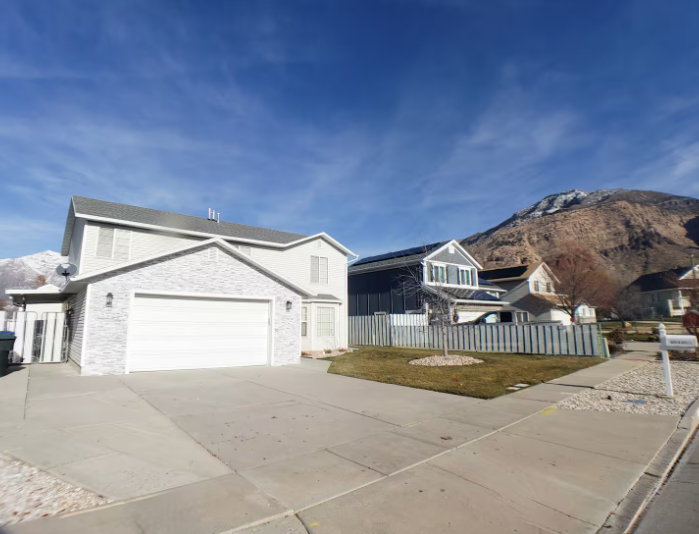 Two-story gray and white home with 2-car garage, large driveway and dramatic Wasatch Mountain backdrop