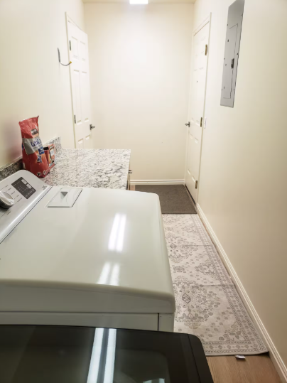 Dedicated laundry room with full-size washer and dryer, folding counter and storage