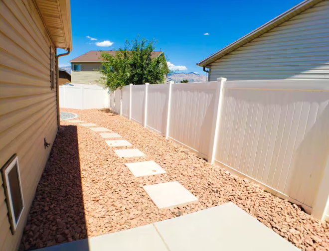Residential backyard with white fence and pathway