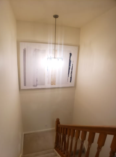 Stairwell landing with wooden banister, modern pendant chandelier and large abstract art print