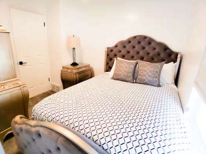 Elegant queen bedroom with tufted velvet headboard, gold nightstand and geometric bedding