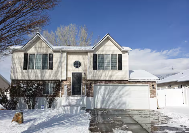 Two-story home with brick accents, black shutters, 2-car garage and snow-covered front yard in winter