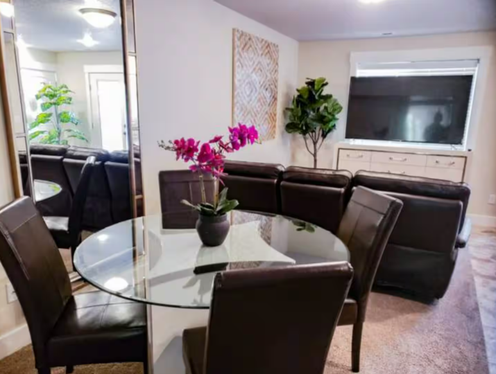 Open dining and living area with glass table, leather seating and flat screen TV