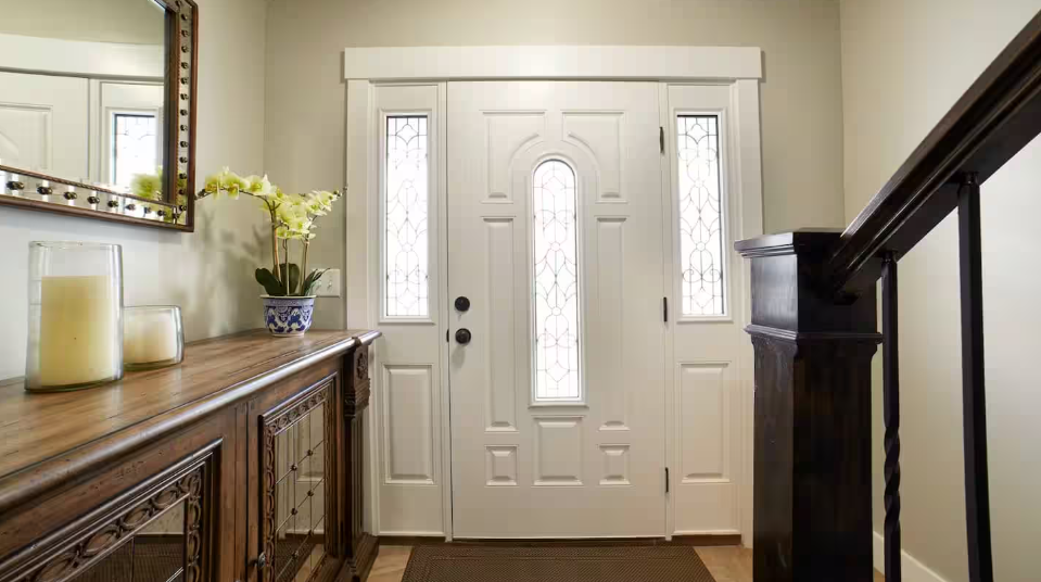 Elegant entryway with white double doors, dark wood staircase and orchid arrangement