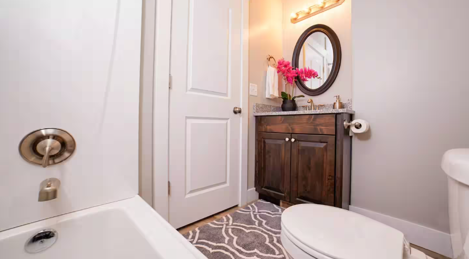 Full bathroom with tub, dark wood vanity and oval mirror