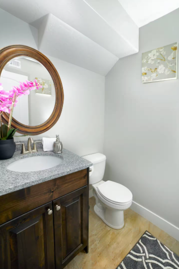 Half bath with granite vanity and round mirror