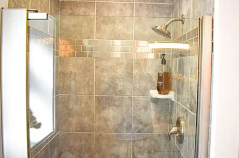 Tiled walk-in shower with glass door and rainfall showerhead