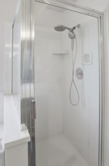 Walk-in shower with glass sliding door, chrome rainfall showerhead and hand wand, white tile surround