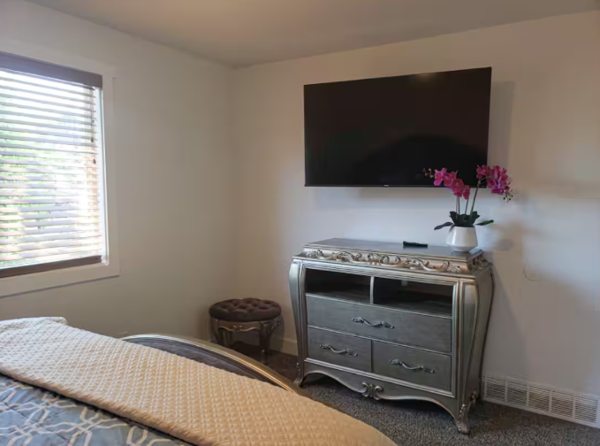 Bedroom with wall-mounted TV and ornate silver dresser