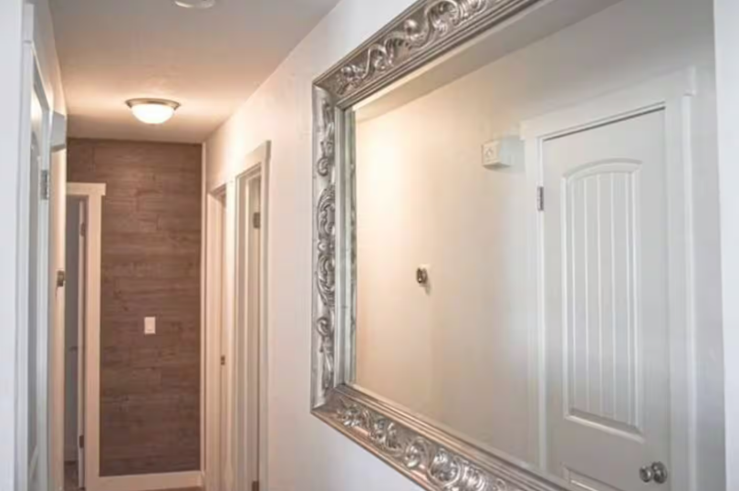 Bright hallway with ornate silver mirror and wood-plank accent wall
