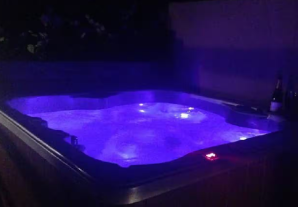 Private hot tub glowing with blue LED lighting at night