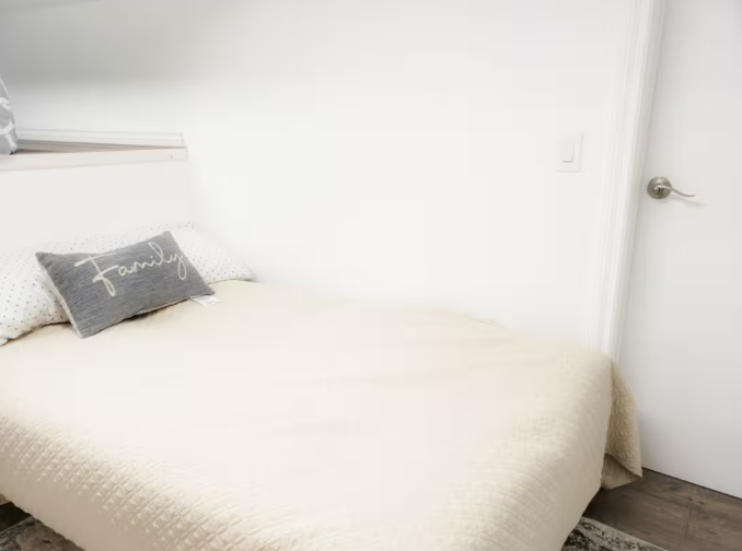 Simple bright bedroom with cream bedding and Family accent pillow