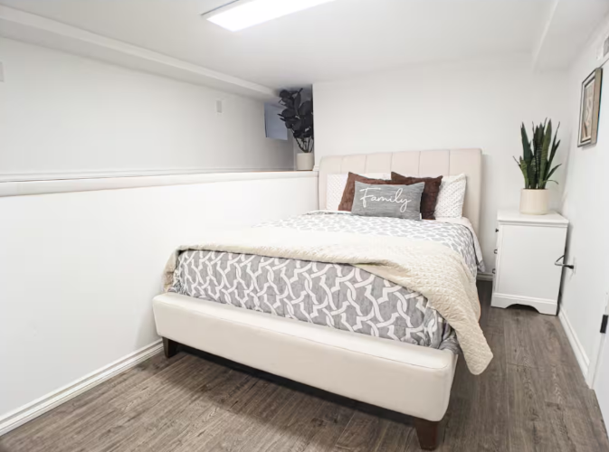 Bedroom with upholstered headboard, patterned bedding, and potted plants