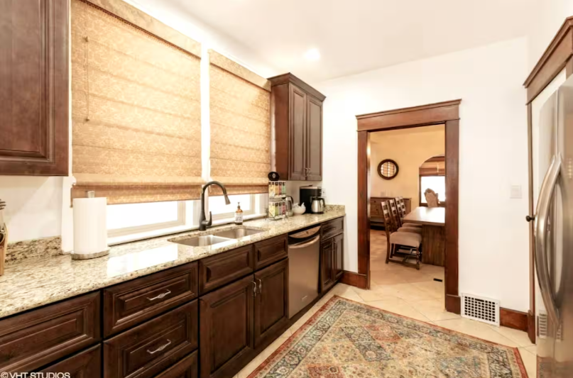 Kitchen with dark cabinetry, granite countertops, and view to dining room