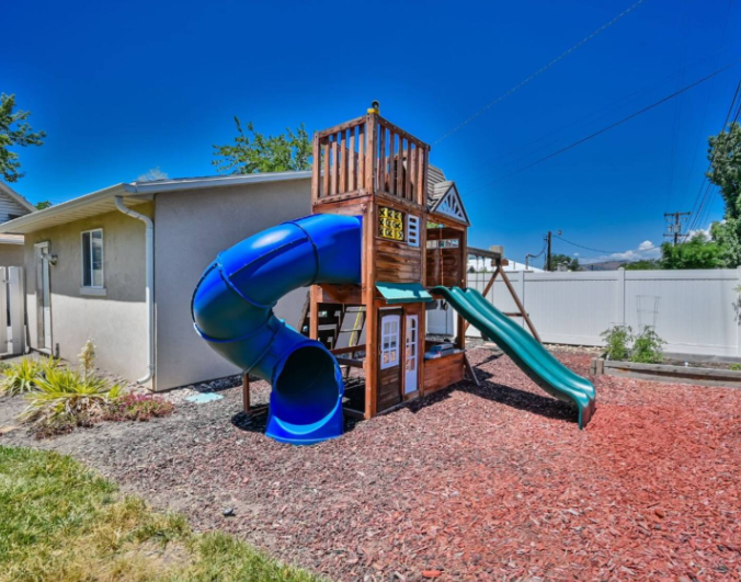 Backyard wooden playground set with blue tube slide and green slide