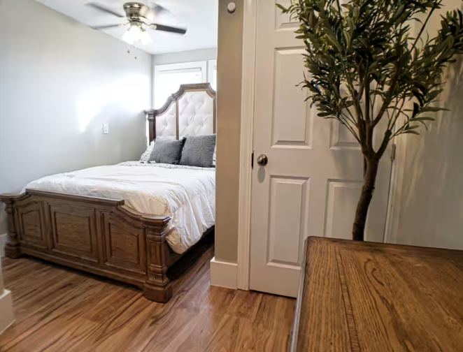 Bedroom with ornate wooden bed frame, tufted headboard, and hardwood floors