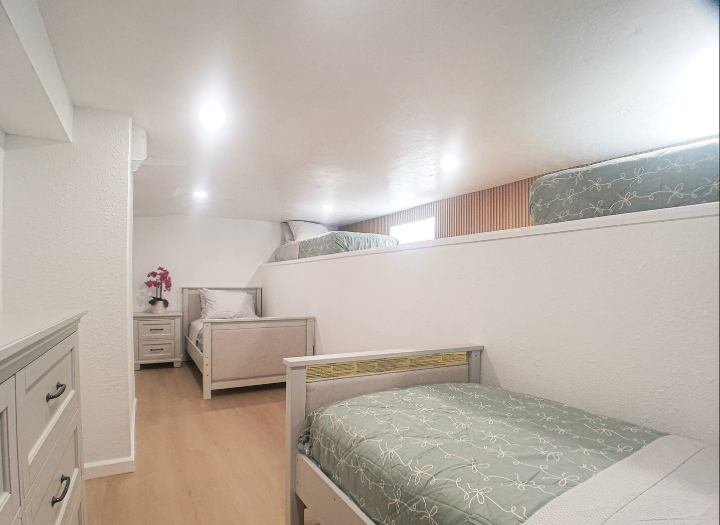 Lower-level bunk room with multiple twin beds and sloped ceiling