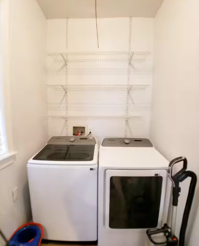 In-unit laundry room with washer, dryer, and wire shelving