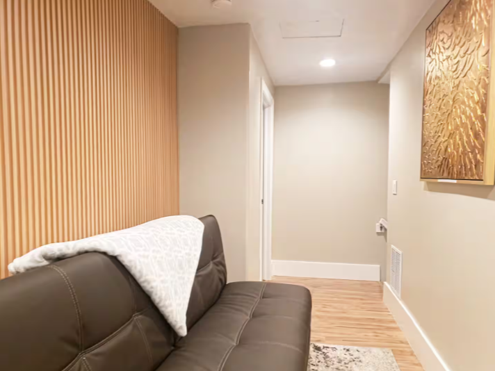 Lower level lounge area with wood slat accent wall and leather sofa