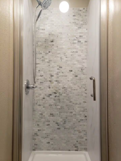 Walk-in shower with white marble mosaic tile and chrome rainfall showerhead
