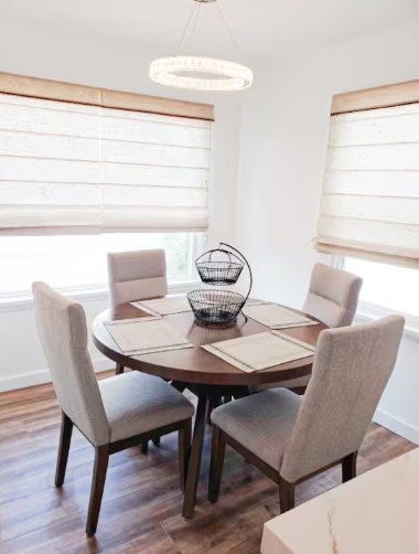 Dining room with round table, upholstered chairs and chandelier