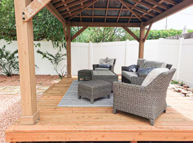 Cedar gazebo deck with wicker lounge furniture and white fence
