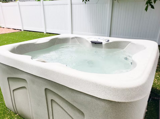 Private hot tub with turf lawn and white vinyl fence