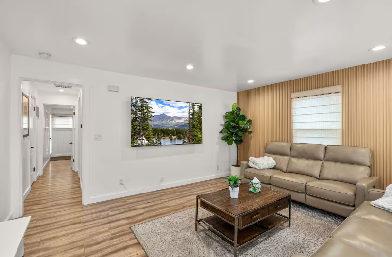 Living room with leather sofa, wood slat wall and mounted TV